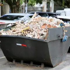 Kontener pełen gruzu budowlanego, cegieł i resztek materiałów. Zastanawiasz się, gdzie wywieźć gruz? Ten widok sugeruje, że problem jest aktualny.