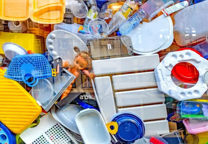 Kolorowy stos plastikowych odpadów, w tym butelki, pojemniki i zabawki. To przykład tego, co to są surowce wtórne.