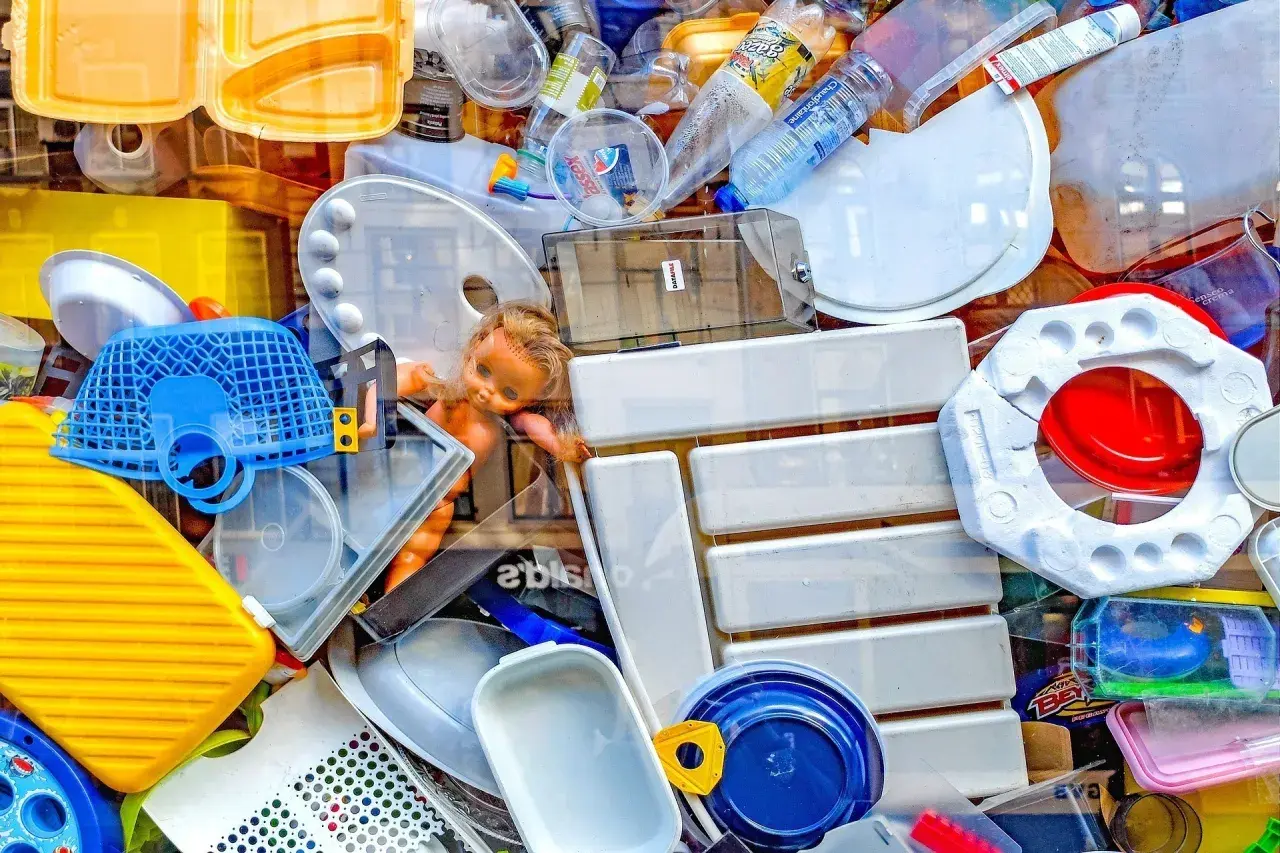 Kolorowy stos plastikowych odpadów, w tym butelki, pojemniki i zabawki. To przykład tego, co to są surowce wtórne.