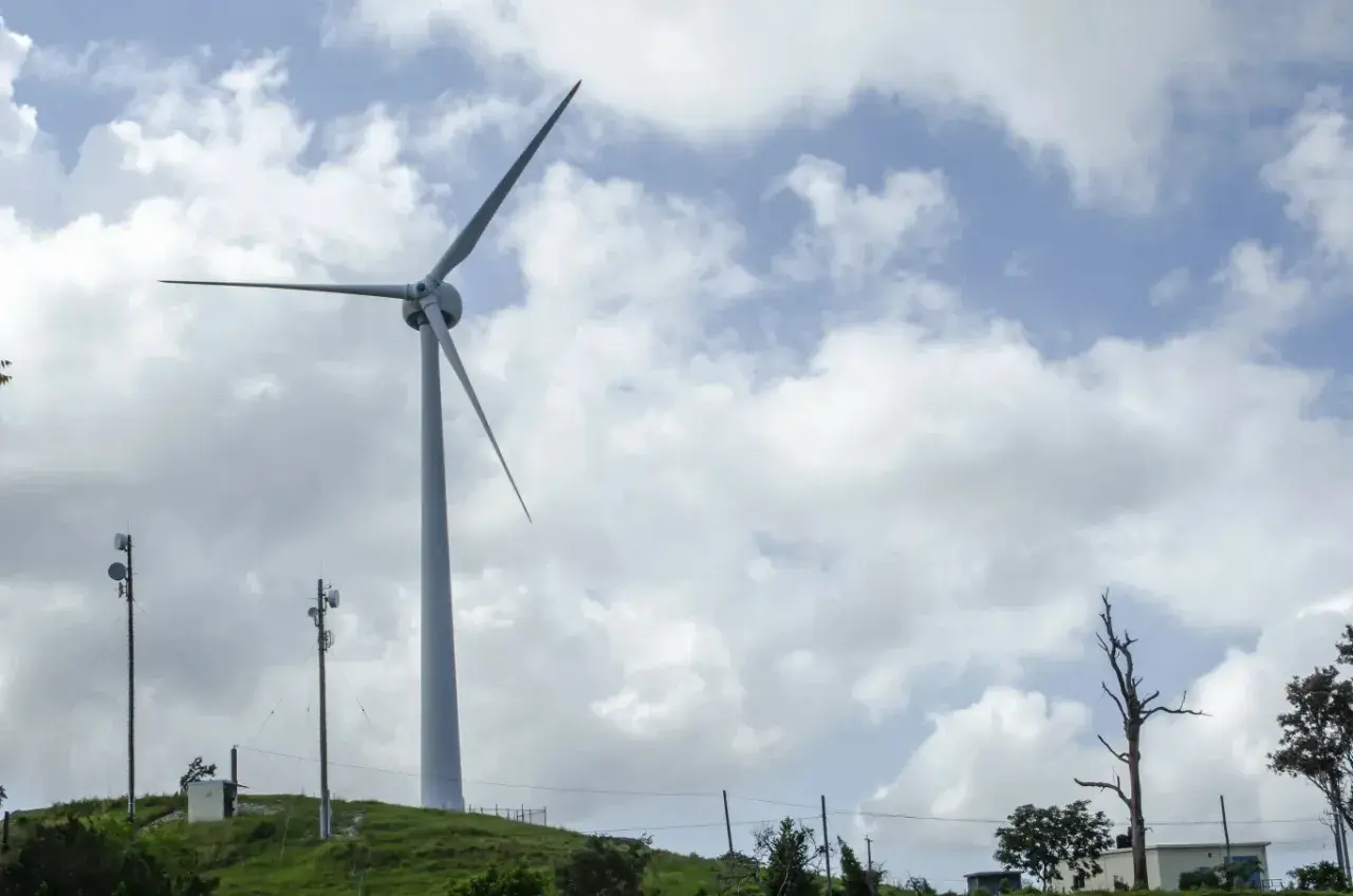 Wiatrak na wzgórzu symbolizuje rozwój energii odnawialnej w Polsce.