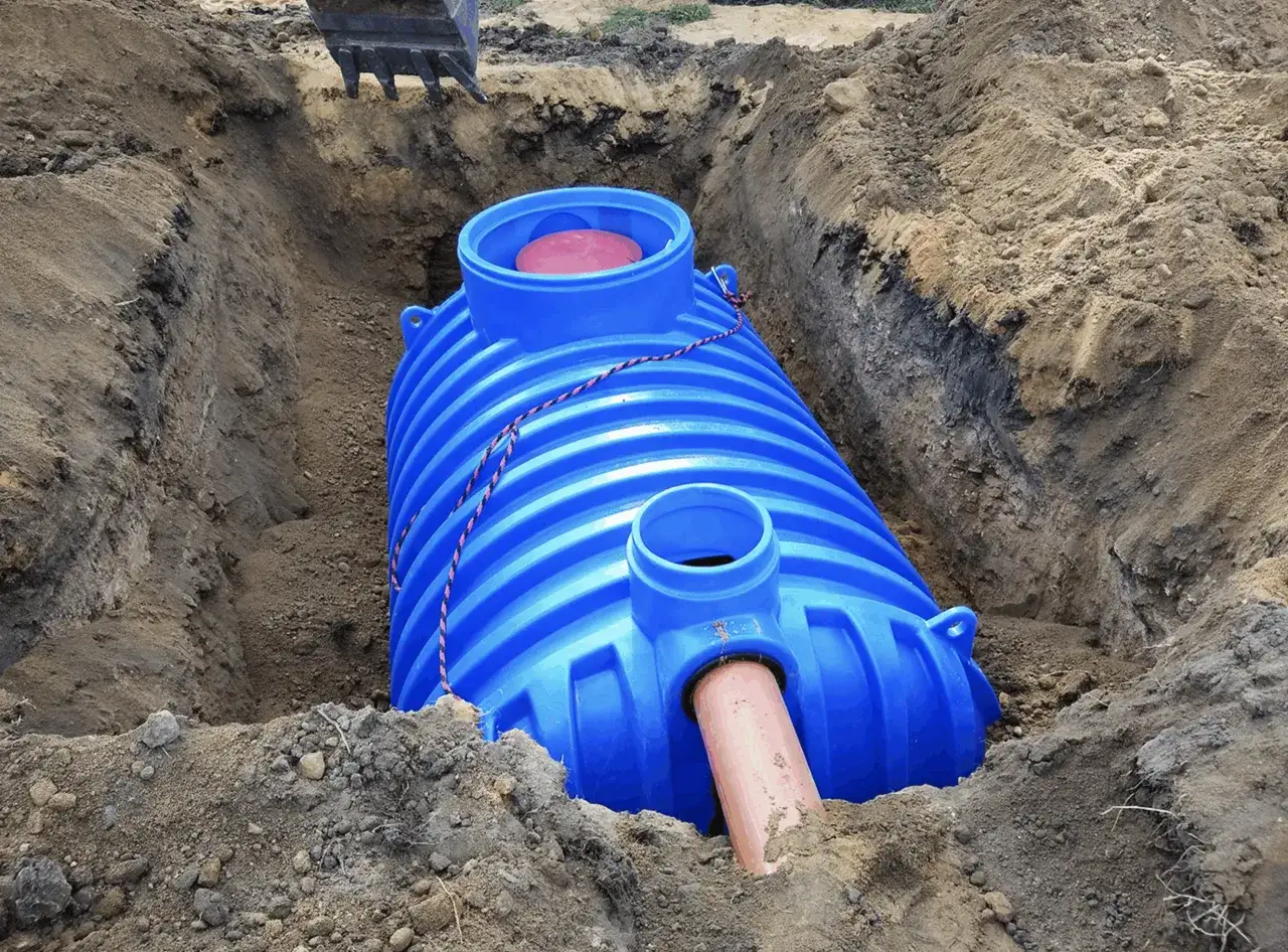 Instalacja niebieskiego zbiornika oczyszczalni ścieków w wykopie. Dowiedz się, ile kosztuje budowa przydomowej oczyszczalni ścieków.