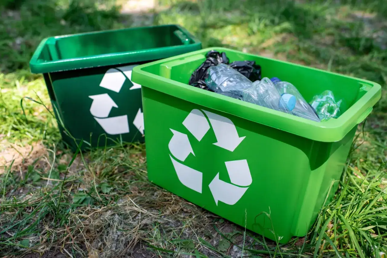 Zielone pojemniki z symbolem recyklingu, gotowe do segregacji odpadów zgodnie z nowymi ustawami o odpadach.